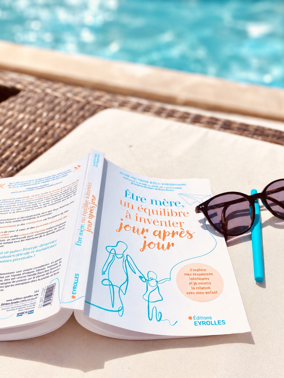 Le livre « Être mère, un équilibre à inventer jour après jour » ouvert au bord d'une piscine
